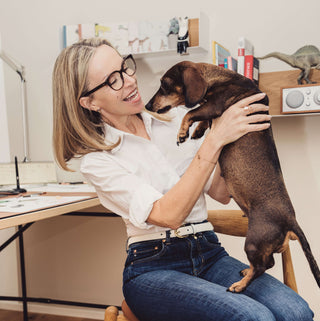 Bild der Shop-Besitzerin Marion Lesnik, auf dem Boden knieend mit ihrem Dackel.