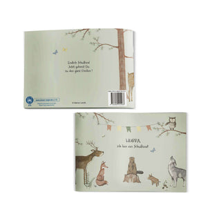 Cover des Einschulungsbuchs "Hurra, ich bin ein Schulkind", zeigt Waldbewohner, Bäume, bunte Wimpel, weicher grüner Hintergrund.