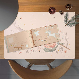 Freundebuch mit Meerjungfrau- und Einhornmotiven, auf einem Holztisch, dekoriert mit Kiefernzapfen, Zweigen und festlichen Akzenten.