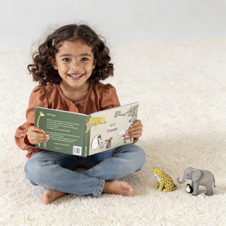 Ein Mädchen sitzt auf einem Teppich, hält das Freundebuch "Beste Freunde Tiere dieser Welt" mit Tierillustrationen.