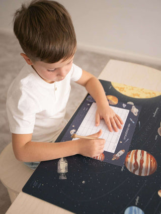 Kind füllt Stundenplan mit Weltraumdesign aus, umgeben von Planeten und Raketen, perfekt zum Schulanfang und für Schultüte.