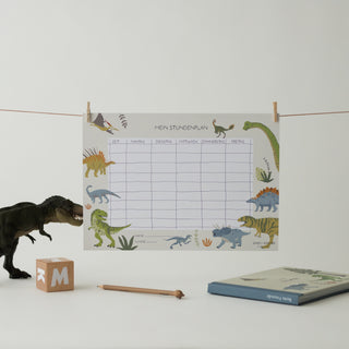 Stundenplan für die Grundschule mit ganz vielen Dinosauriern. Daneben ist eine T-Rex Figur, ein Bleistift und das Kinderfreundebuch Dinosaurier zu sehen.