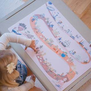 Mädchen entdeckt Zeitreise-Unterlage rosa: Kleines Mädchen zeigt mit dem Finger auf verschiedene historische Epochen auf der rosa Kinderschreibtischunterlage. Interaktives Lernen und Entdecken der Geschichte.
