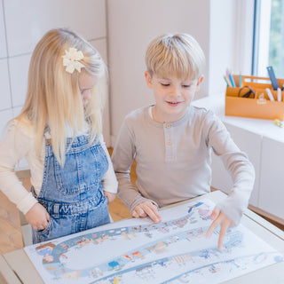 Glückliche Kinder mit Schreibtischunterlage Geschichte: Junge lächelt beim spielerischen Lernen der Menschheitsgeschichte auf der hochwertigen Kinderschreibtischmatte. Ideal für Kindergarten und Grundschule.