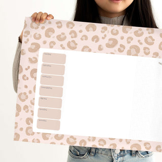 Leopard-print Wochenplaner "Leo", gehalten von Kind, enthält Wochentage, großen Schreibbereich, dekoratives Muster, rosa Töne.