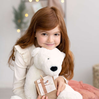 Mädchen hält einen großen weißen Teddybären und ein Adventskalender-Päckchen im DIY-Stil in der Hand.