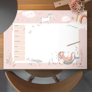 Papierblock-Unterlage "Mermaid" Wochenplaner mit illustrativer Meerjungfrau, Einhorn und Delfin, pastellfarben auf Holzoberfläche.