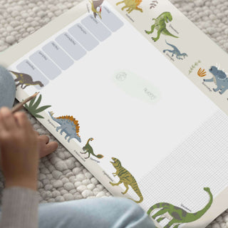 Illustrierter Wochenplanerblock mit verschiedenen bunten Dinosauriern an den Rändern, mit Platz für Notizen und einem Rasterbereich.