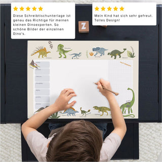 Kinderschreibtisch mit Illustrierter Wochenplanerblock mit verschiedenen bunten Dinosauriern an den Rändern, mit Platz für Notizen und einem Rasterbereich. Sowie zwei Kundenbewertungen.