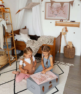 Zwei Mädchen sitzen auf dem Boden im Kinderzimmer und betrachten  die Kinderschreibtischunterage Weltkarte der Tiere in rosa.