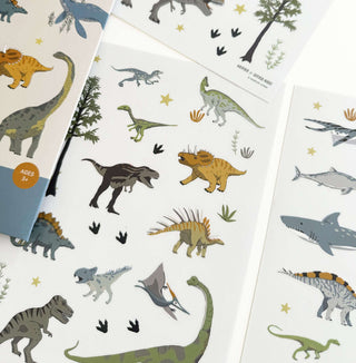 Mega Dino-Sticker Set mit transparenten Bögen zeigt verschiedene Dinosaurier, prähistorische Reptilien, Bäume und Sterne.