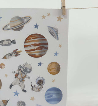 Transparente Aufkleber mit Weltraummotiven wie Planeten, Astronauten, Raketen und Sterne, die eine verspielte Weltraumatmosphäre schaffen.