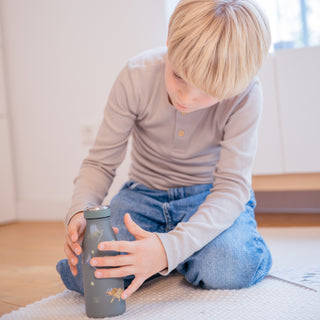 Ein Dino-Sticker wird auf eine Trinkflasche für Kinder aufgeklebt. Auf der Trinkflasche kleben bereits verschiedene Dinosicker mit transparentem Hintergrund.