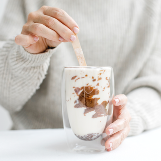 Trinkschokolade wird in einer transpareten Tasse, in Milch, angerührt.
