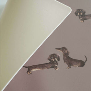 Abwaschbare Schreibtischunterlage in Taupe mit Dackel-Motiven, zeigt niedliche, stilisierte Dackel-Illustrationen auf der Oberfläche.