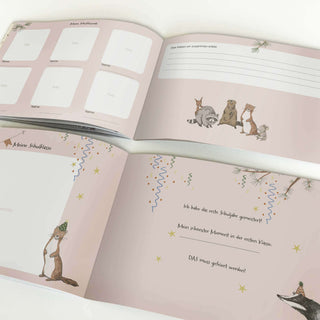 Einschulungsbuch in Rosa, aufgeklappt; illustriert mit Fuchs und Waschbär; Felder für Fotos, Notizen; feierliches Design.